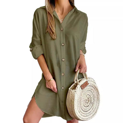 Woman wearing olive green button-up shirt dress with rolled sleeves holding round woven straw handbag
