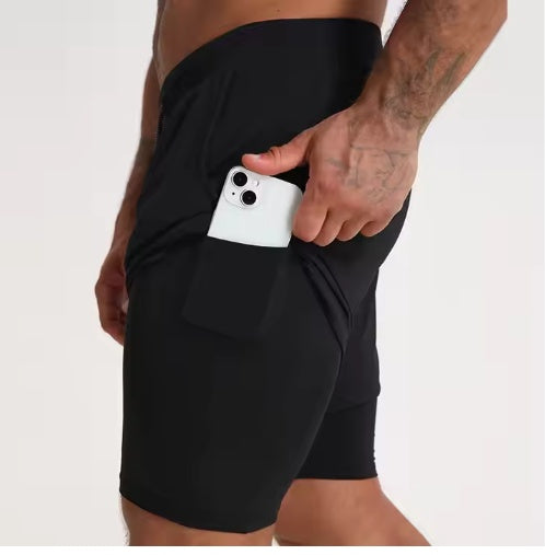 Close-up of a man wearing black athletic shorts with a side pocket holding a white smartphone