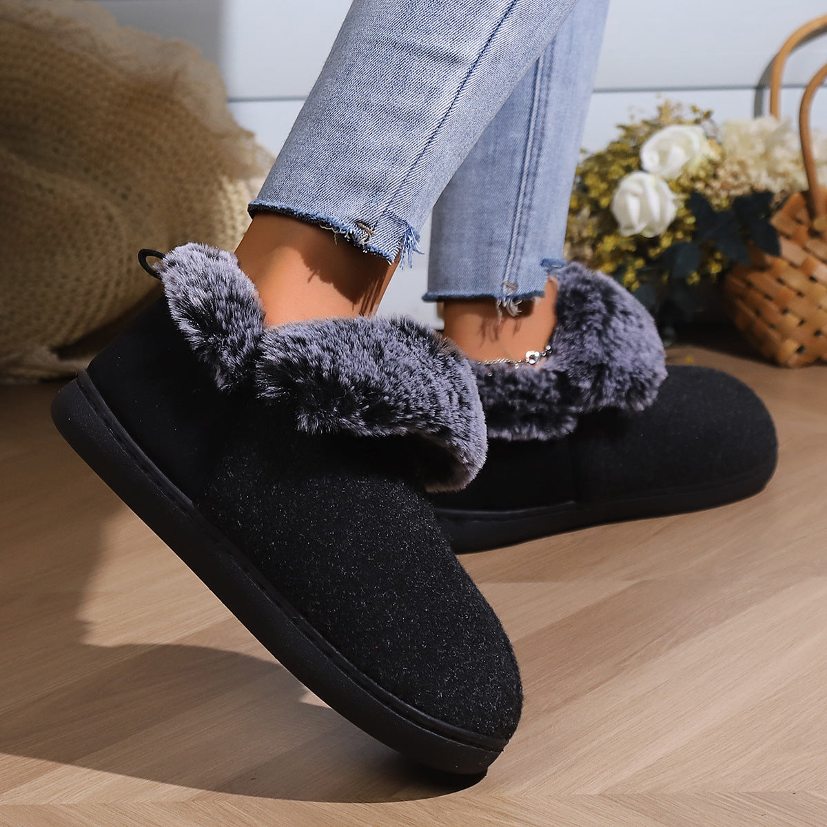 Black cozy slip-on slippers with gray faux fur lining worn with frayed light blue jeans