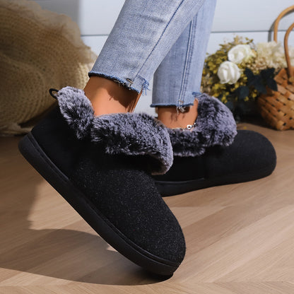 Black cozy slip-on slippers with gray faux fur lining worn with frayed light blue jeans
