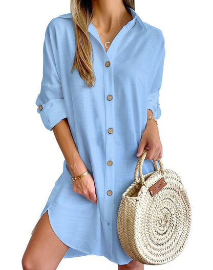 woman wearing light blue button-down shirt dress holding woven straw round handbag