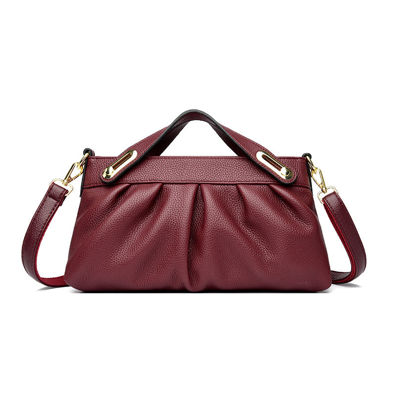Elegant maroon leather handbag with pleated design, gold hardware, top handle, and detachable shoulder strap