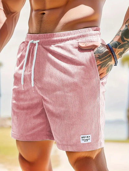 Close-up of a man wearing pink corduroy shorts with white drawstring and tattooed arm outdoors