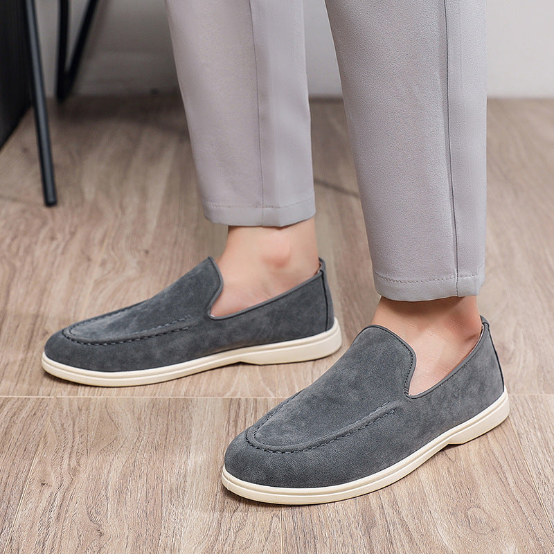 grey suede slip-on casual shoes with white soles worn with light grey pants on wood floor