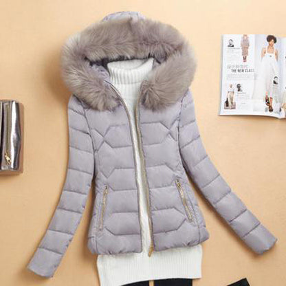 Light gray quilted winter jacket with fur hood and gold zipper, displayed on white sweater background