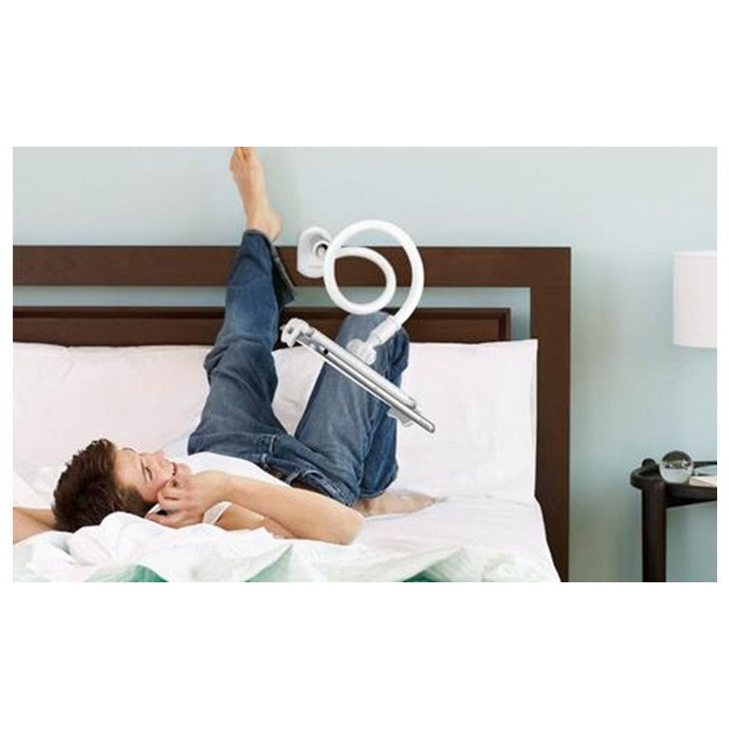 Boy lying on bed with legs raised holding white spiral flexible hose in cozy bedroom