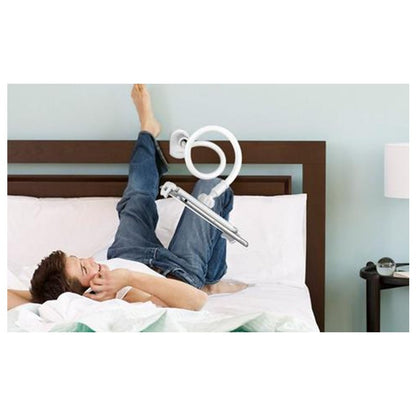 Boy lying on bed with legs raised holding white spiral flexible hose in cozy bedroom