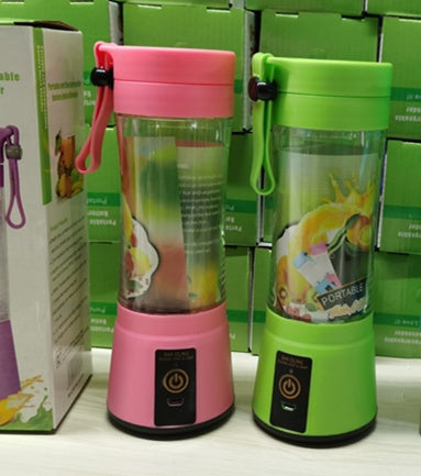 Portable pink and green electric juice blenders with power buttons displayed on a store shelf