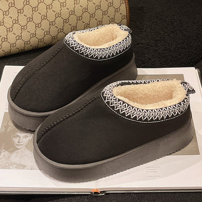 Black slip-on winter slippers with fluffy beige lining and decorative white stitching on edges