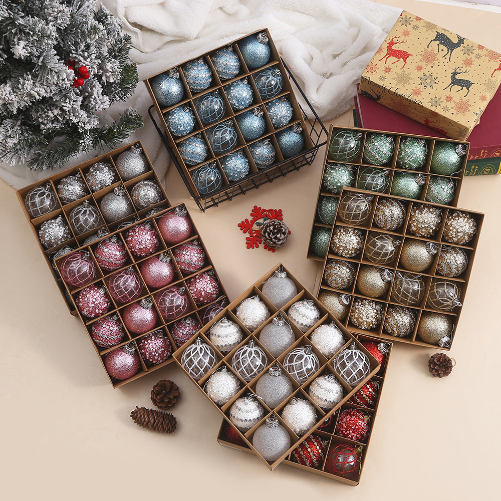 Boxes of assorted blue, red, green, silver, and gold Christmas ornaments with pinecones and a snowy Christmas tree