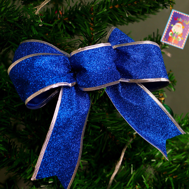 Sparkling blue glitter Christmas bow with silver edges on green pine tree branch