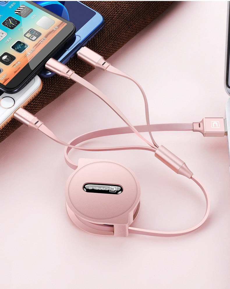 Rose gold retractable multi-device charging cable connected to smartphones and laptop on pink surface