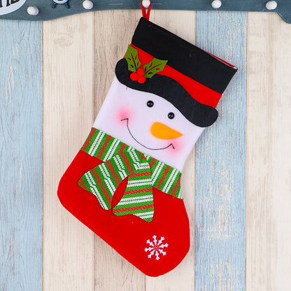 Christmas stocking with smiling snowman face, black top hat, green striped scarf, and red snowflake on wooden background