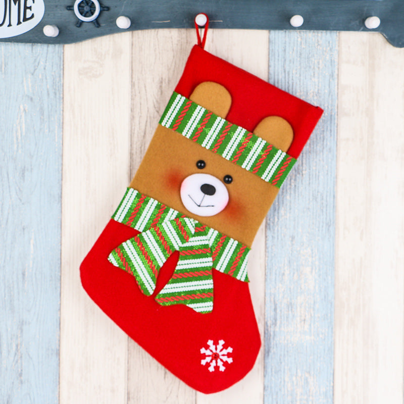Red Christmas stocking with a cute bear face wearing a green striped scarf and hat, snowflake detail