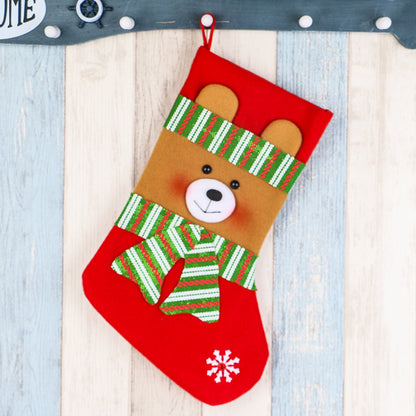 Red Christmas stocking with a cute bear face wearing a green striped scarf and hat, snowflake detail
