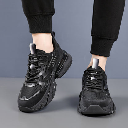 Person wearing black chunky sneakers with textured design and black jogger pants on gray floor