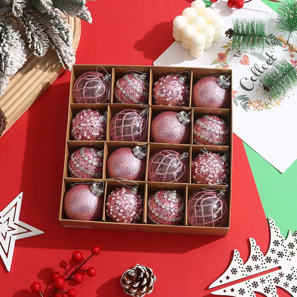 Box of pink glitter and sequined Christmas baubles on a red holiday table with pine branches and holiday decor