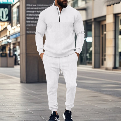 Man wearing white cable knit zip-up sweater and matching joggers with black sneakers on city street