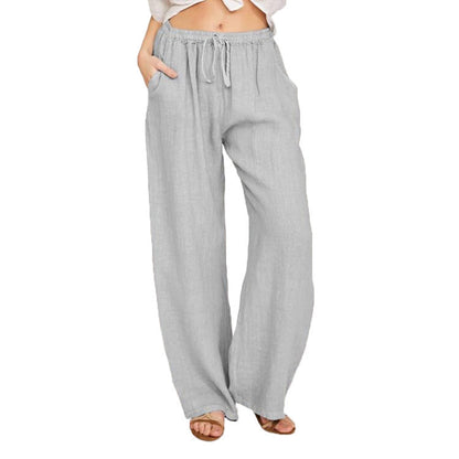 Woman wearing light gray wide-leg linen pants with drawstring waist and pockets, styled casually