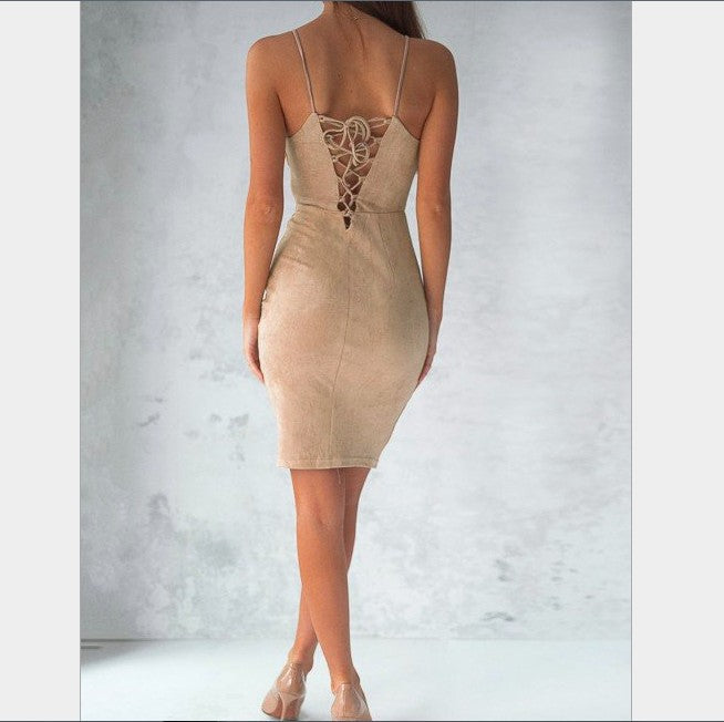 Woman wearing a beige bodycon dress with lace-up back detail and thin straps, posing against gray wall
