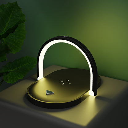 Modern black and gold desk lamp with arched LED light and wireless charging pad on table