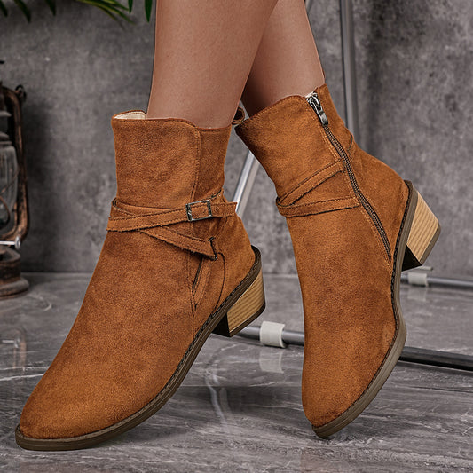 Brown suede ankle boots with side zipper and buckle strap, worn on marble floor