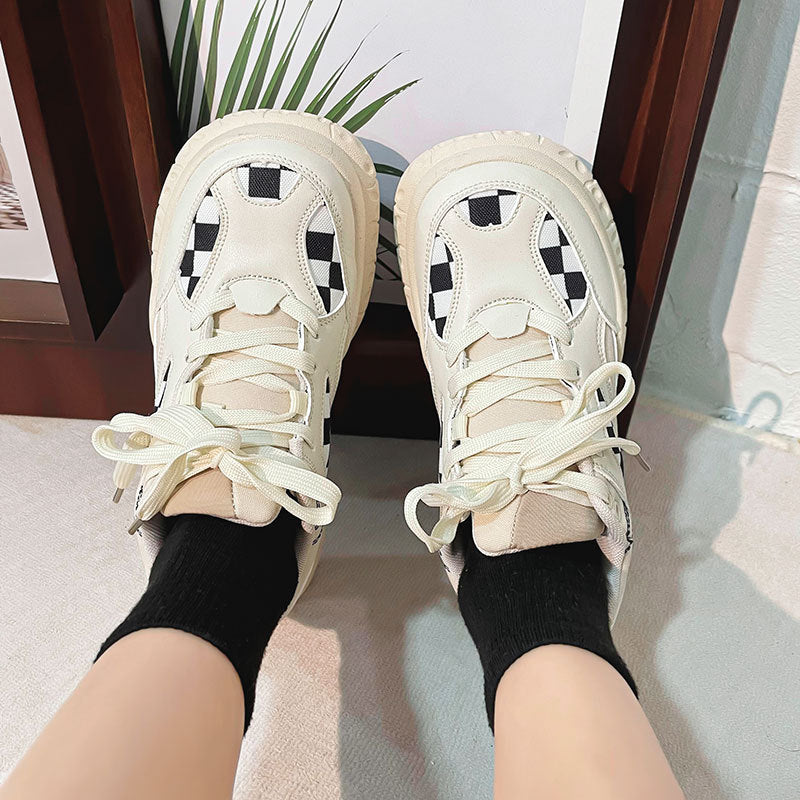 Close-up of beige sneakers with black and white checkerboard pattern worn with black socks indoors