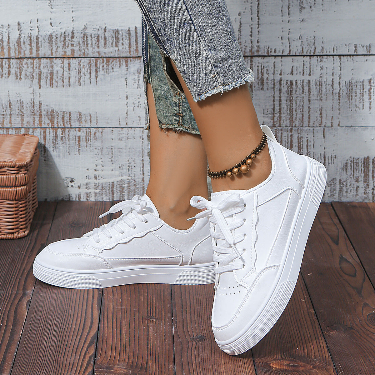 White platform sneakers with laces worn with blue frayed hem jeans and bronze beaded ankle bracelet
