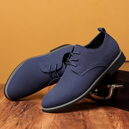 Pair of stylish navy blue men's dress shoes on wooden surface with tan background