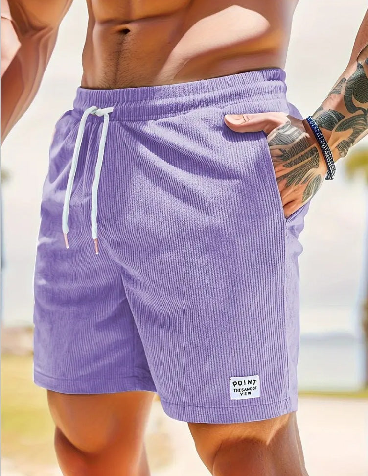 Close-up of a muscular man wearing purple corduroy shorts with white drawstrings and tattooed arm