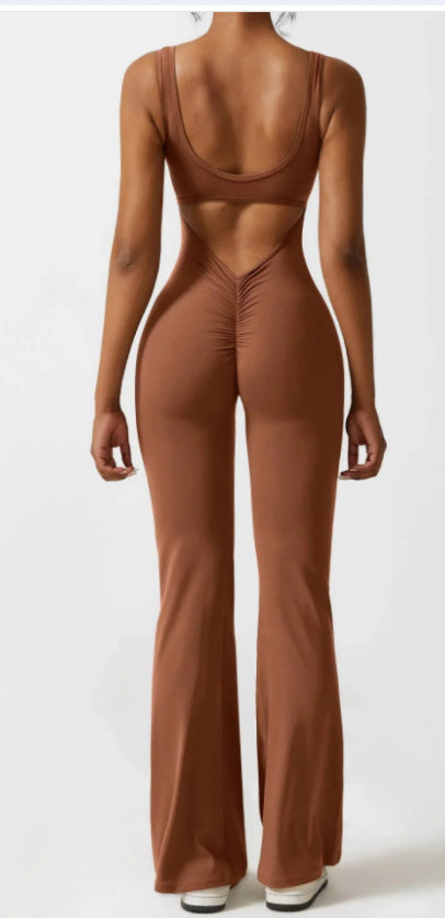 Back view of woman in brown sleeveless cutout jumpsuit with ruched detail and white shoes