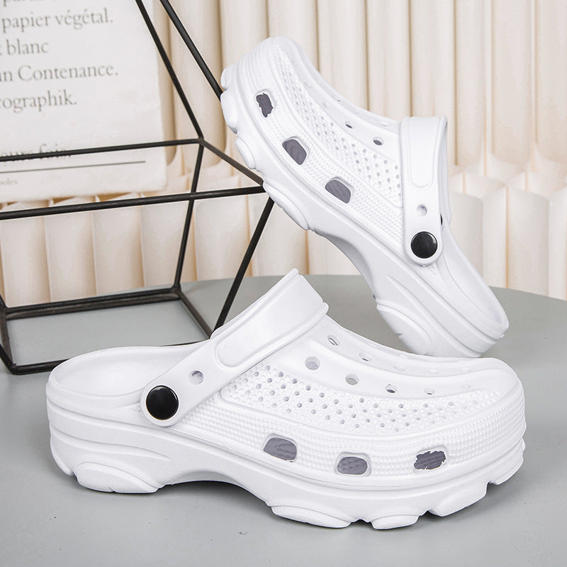 Pair of white perforated slip-on clogs with black button accents on gray surface