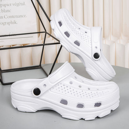 Pair of white perforated slip-on clogs with black button accents on gray surface