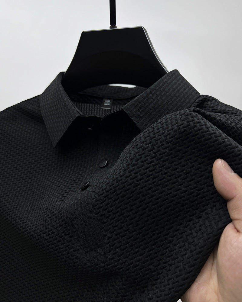 Close-up of black textured polo shirt with collar and buttons held by hand on black hanger