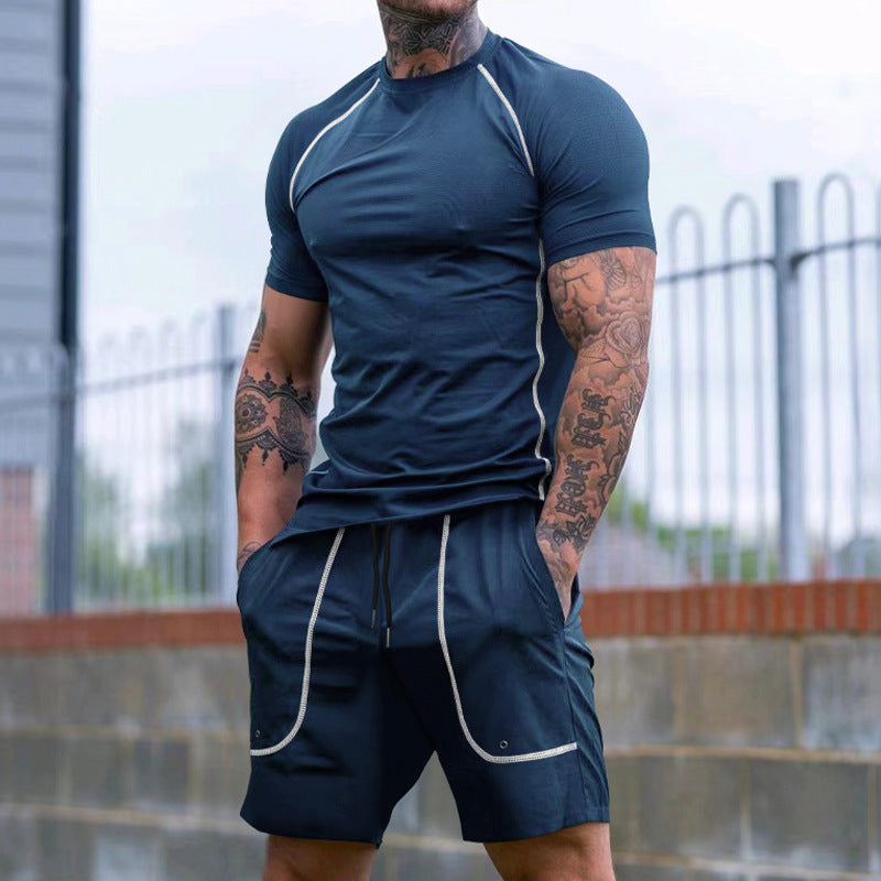 Muscular man with tattoos wearing navy athletic t-shirt and matching shorts with white piping outdoors