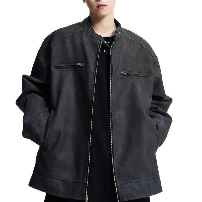 Person wearing a black suede bomber jacket with zippered chest pockets and hands in side pockets