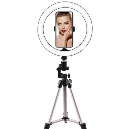 Ring light on tripod with smartphone holder displaying a woman with red lipstick and nails