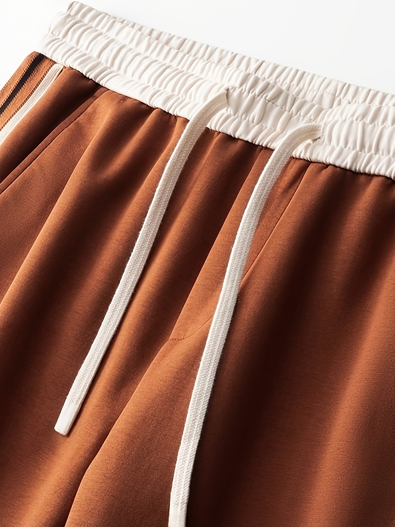 Close-up of brown sweatpants with white elastic waistband and drawstrings