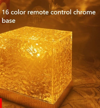 Illuminated textured glass cube lamp with warm amber glow on chrome base with 16-color remote control