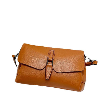 tan pebbled leather crossbody bag with flap and buckle closure on white background