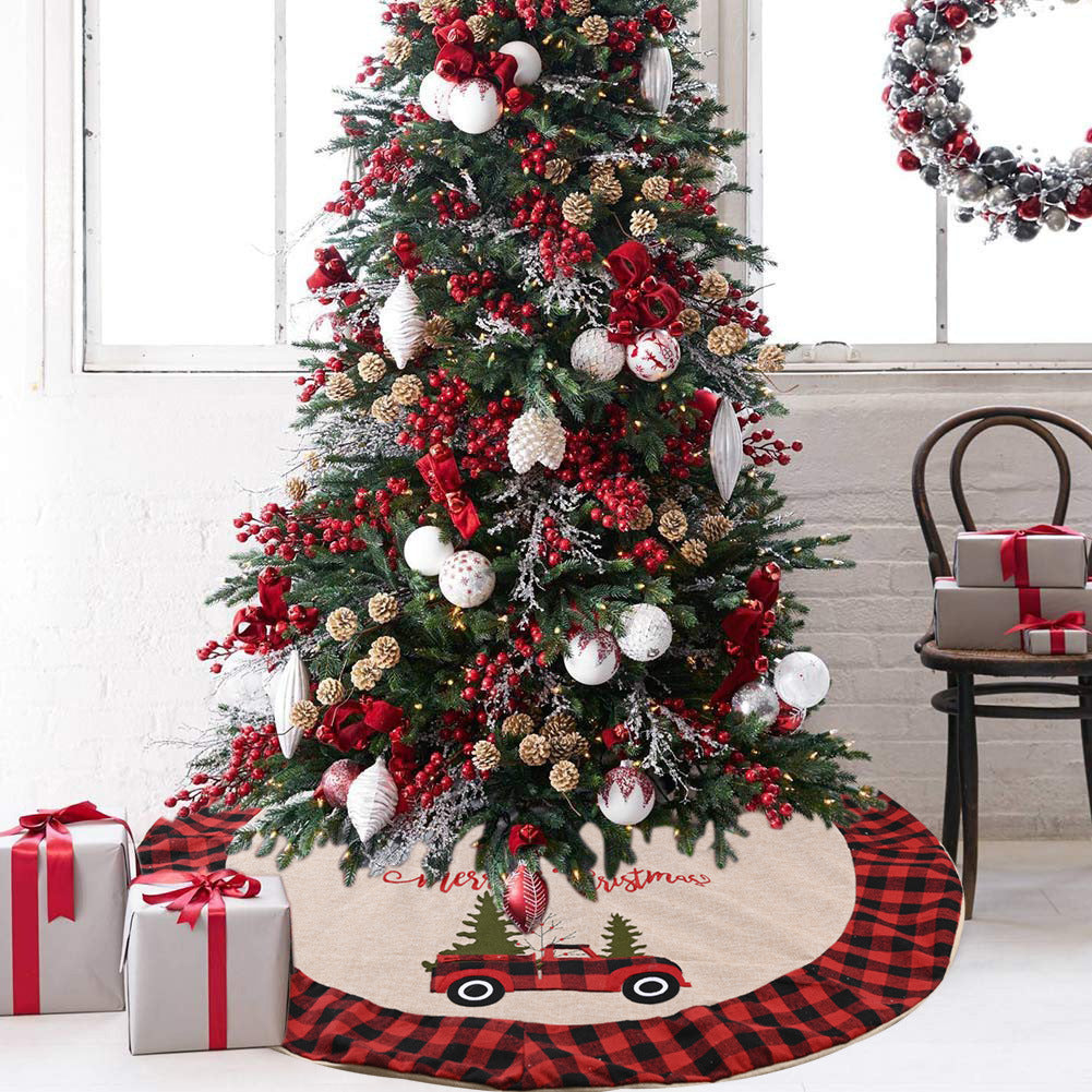 Christmas tree decorated with red berries, gold pine cones, white ornaments, red bows, plaid tree skirt, gifts, and festive wreath