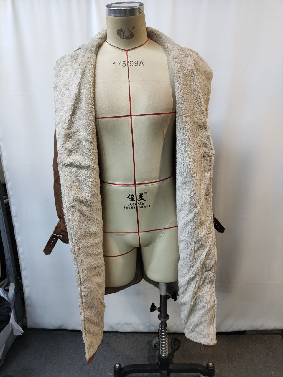 Mannequin wearing open brown jacket with plush beige fur lining against white background