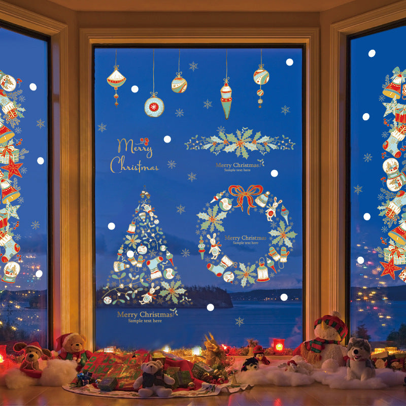 Christmas window decorations with tree, wreath, ornaments, and plush toys arranged on floor by night lake view