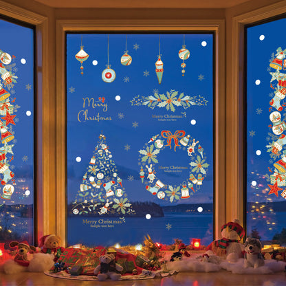 Christmas window decorations with tree, wreath, ornaments, and plush toys arranged on floor by night lake view
