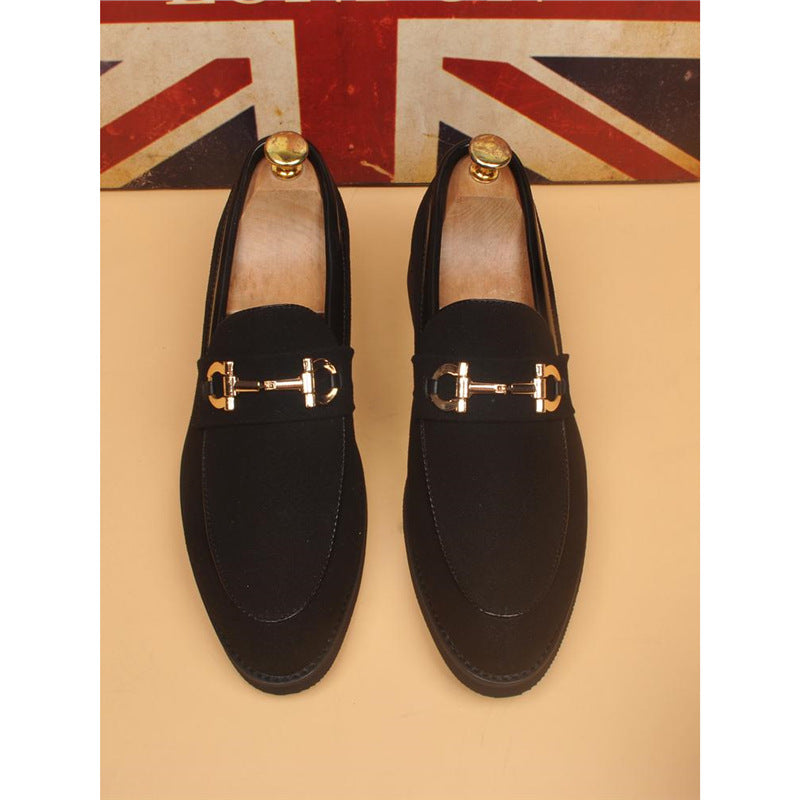 Pair of black men's loafers with gold horsebit detail on beige background and British flag
