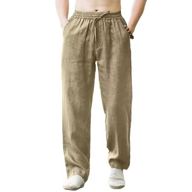 Man wearing beige linen drawstring pants with elastic waistband and pockets on white background