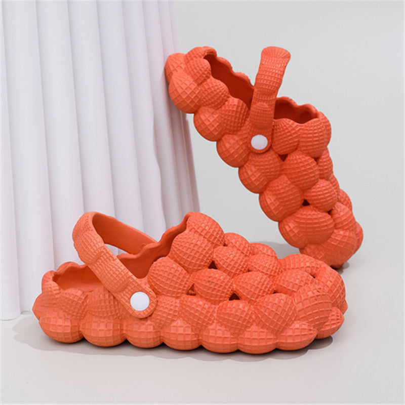 Pair of bright orange bubble-textured clogs with adjustable straps against white backdrop