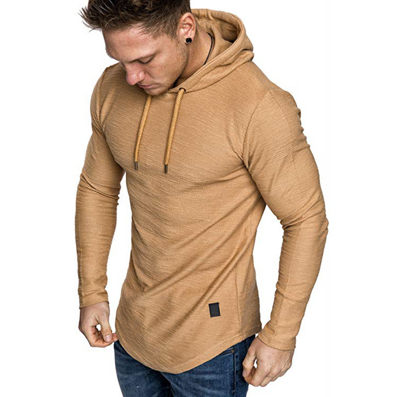 Man wearing fitted tan hoodie with drawstrings and blue jeans on white background