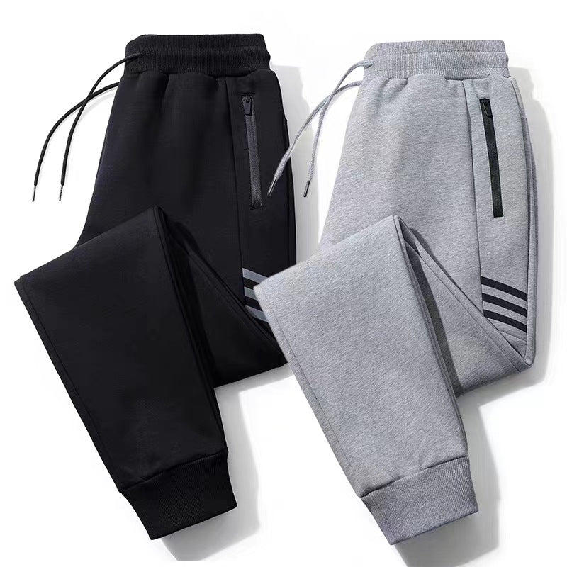 Black and grey casual jogger pants with zippered pockets and drawstring waist on white background