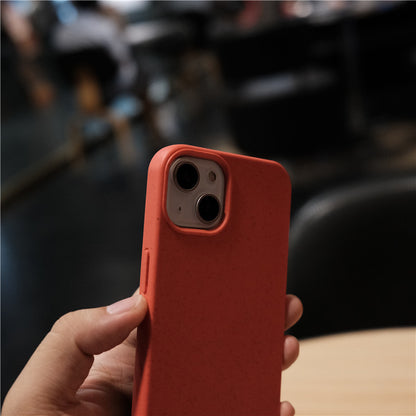 Hand holding smartphone with red protective case in indoor setting